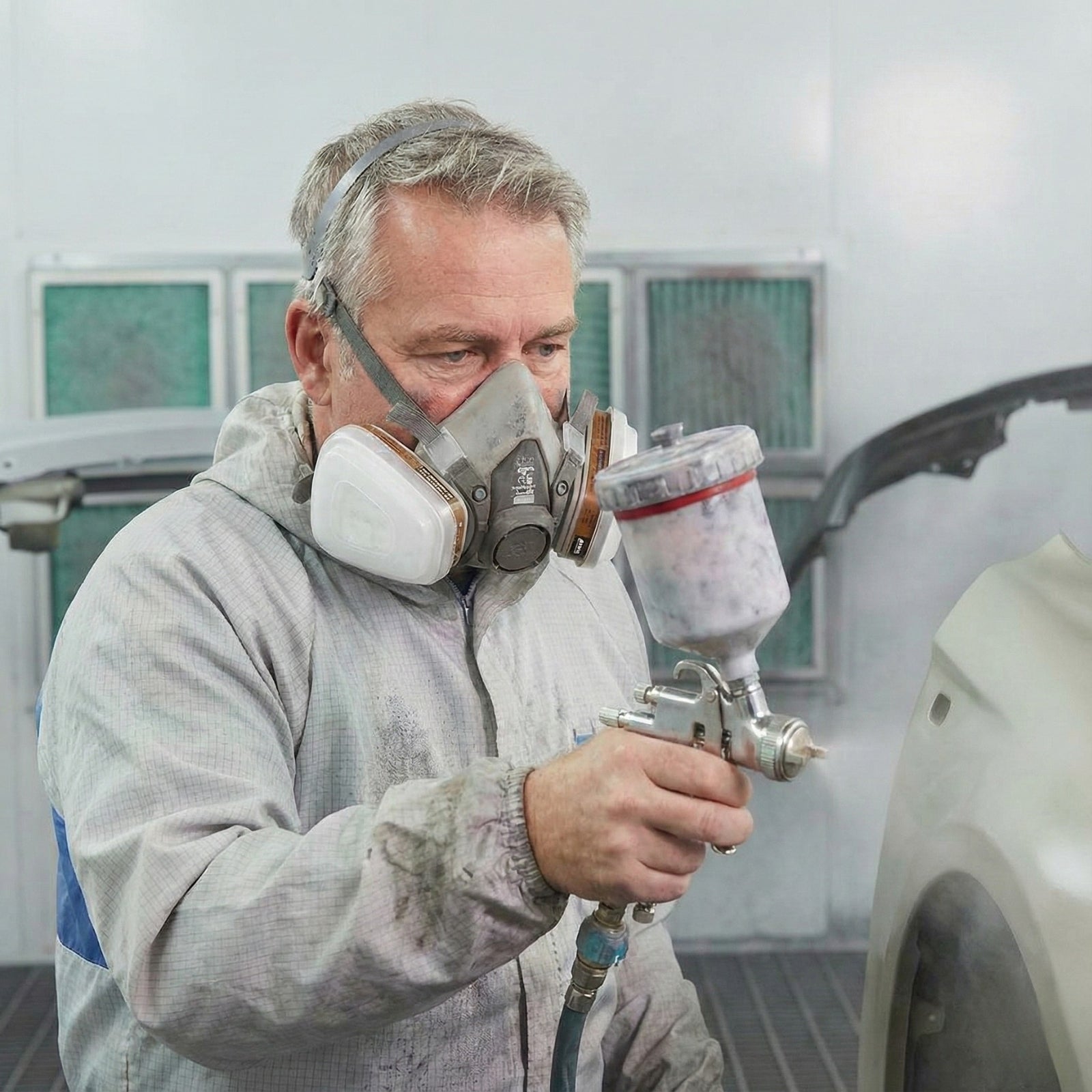 Painter utilizing AMS respirator with A8502 retainer holding pre-filter during spray painting